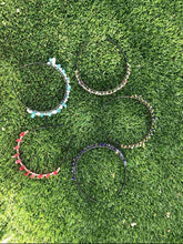 Load image into Gallery viewer, 5 hand made crystal tiaras laying in grass view from overhead
