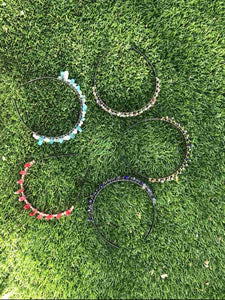5 hand made crystal tiaras laying in grass view from overhead